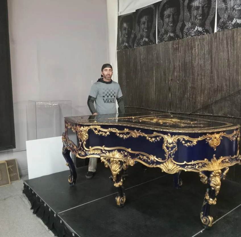 Ornate gilded grand piano on a low platform