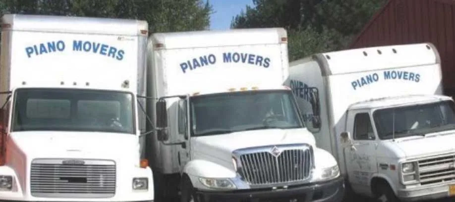 Three piano moving trucks parked side by side