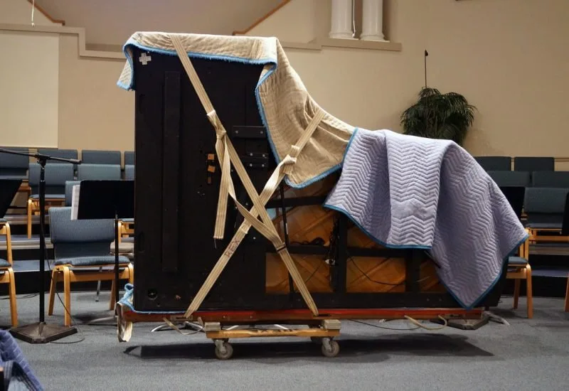 Upright piano wrapped and strapped on a moving dolly