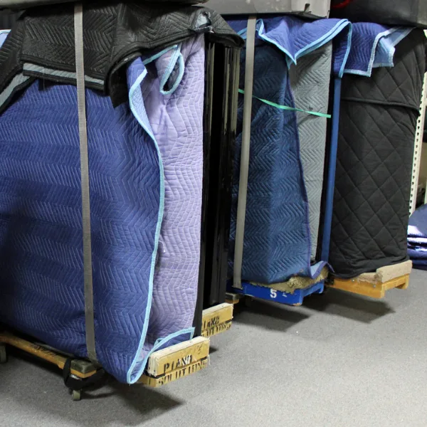 Blanket-wrapped pianos standing on moving boards