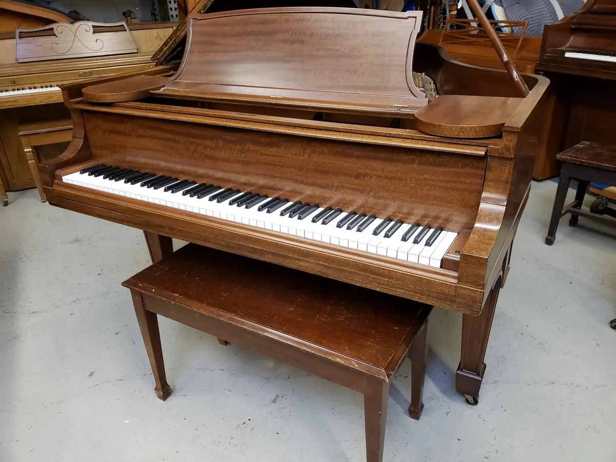 Walnut grand piano with bench in a showroom